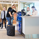 People at airport counter checking in with luggage